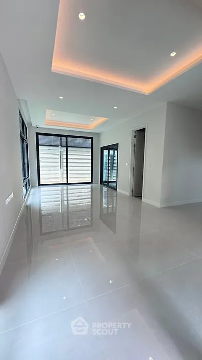 Spacious modern living room with sleek tile flooring and ambient ceiling lighting.