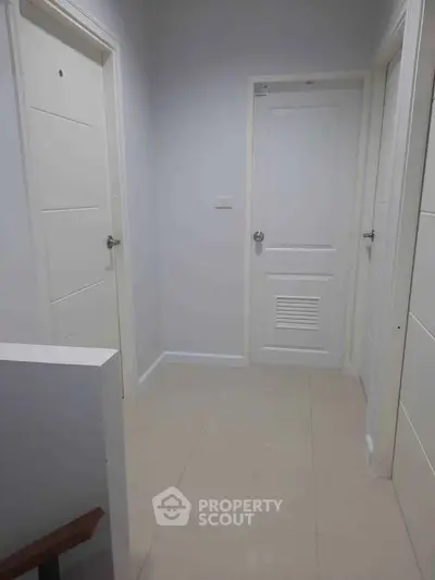 Modern hallway with white doors and tiled flooring in a residential property