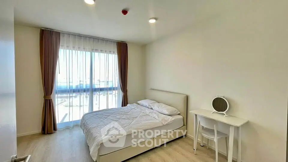 Bright and airy bedroom with modern furnishings and large window offering natural light.