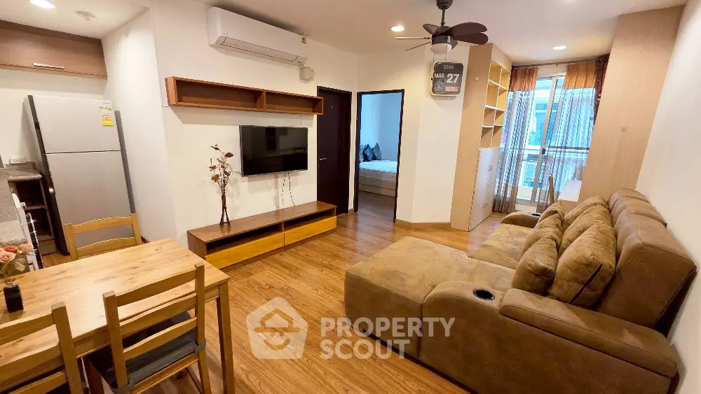 Modern living room with cozy sofa and open layout leading to bedroom and balcony