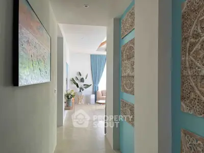 Elegant hallway leading to a bright living area with modern decor and natural light.