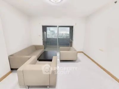 Spacious living room with modern furniture and balcony view in urban apartment.