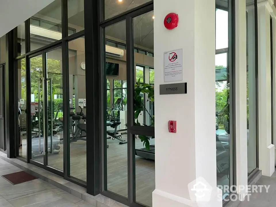 Modern fitness gym with glass walls and lush greenery view