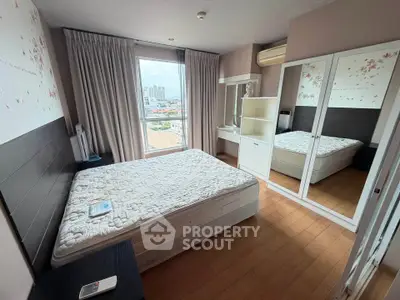 Cozy bedroom with large window and city view, featuring a comfortable bed and mirrored wardrobe.