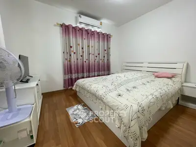 Cozy bedroom with wooden flooring, stylish bed, and vibrant curtains, perfect for a restful retreat.