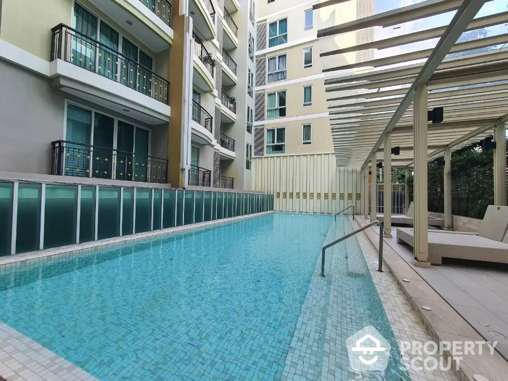 Modern condominium with luxurious swimming pool and stylish outdoor seating area.