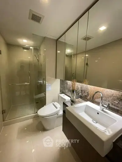 Modern bathroom with glass shower, sleek sink, and elegant lighting.