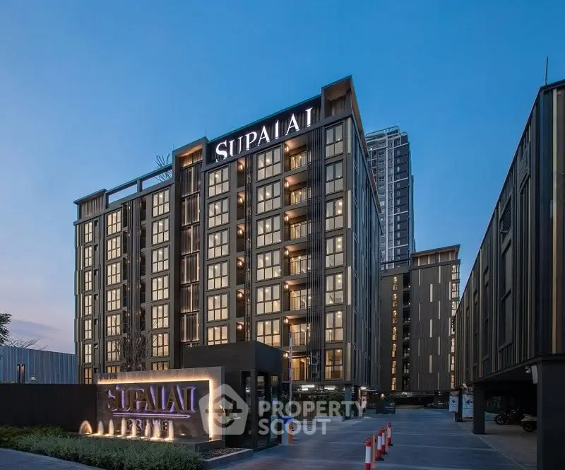 Modern high-rise building exterior with sleek design and illuminated signage at dusk.
