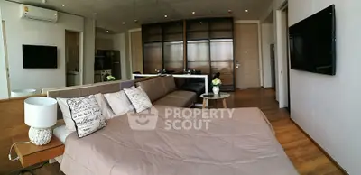 Modern studio apartment with open layout, featuring a cozy bed, stylish sofa, and sleek kitchen area.