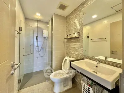 Modern bathroom with glass shower, sleek sink, and contemporary design.