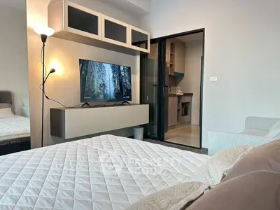 Modern bedroom with TV and open kitchen view, cozy and stylish interior design.