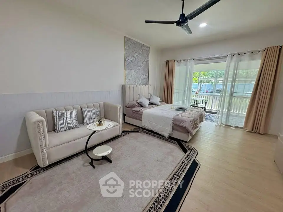 Spacious bedroom with elegant decor and large window offering natural light and garden view.