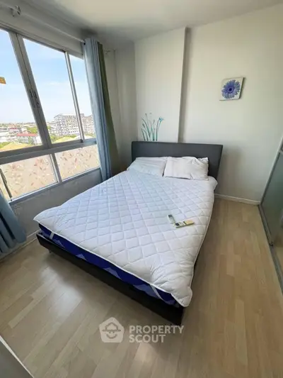 Cozy bedroom with large window offering city views, featuring a comfortable bed and modern decor.