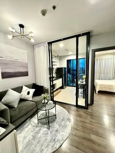 Modern open-plan living room with stylish decor and sliding glass doors leading to a cozy bedroom.