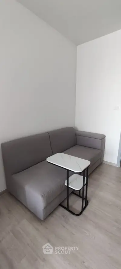 Modern minimalist living room with sleek gray sofa and stylish marble coffee table.