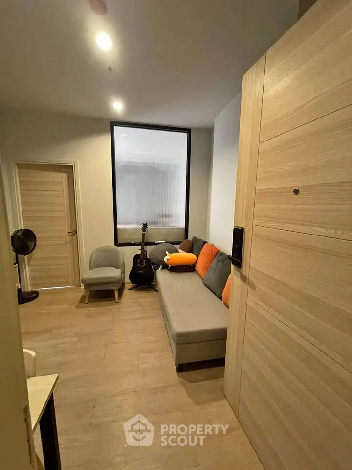 Cozy living room with modern decor and wooden flooring, featuring a comfortable sofa and stylish armchair.