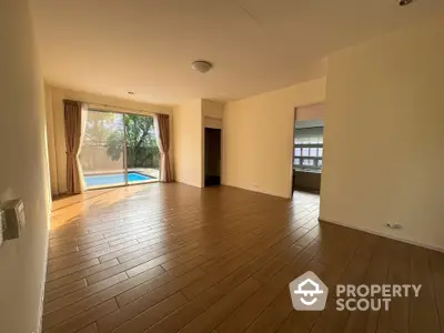 Spacious living room with wooden flooring and pool view, perfect for relaxation and entertaining.