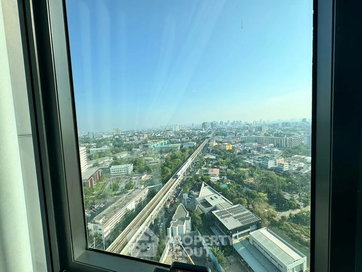 Stunning cityscape view from high-rise window overlooking urban skyline and transit line.