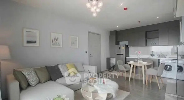 Modern living room with open kitchen, stylish decor, and cozy seating area.