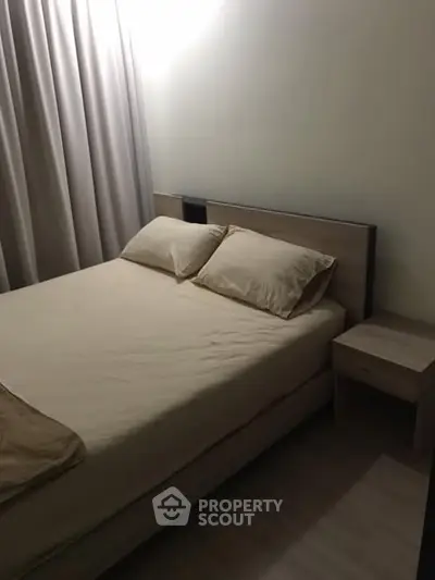 Cozy bedroom with modern wooden bed and nightstand, soft lighting and neutral tones.