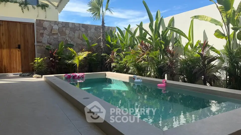 Luxurious private pool surrounded by lush greenery and stone wall, perfect for relaxation and leisure.