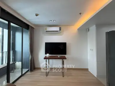 Modern living room with sleek TV setup and balcony access in a stylish apartment.