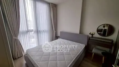 Cozy bedroom with large window and modern furnishings in a stylish apartment.