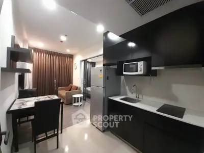 Modern kitchen and living area with sleek black cabinetry and cozy seating.