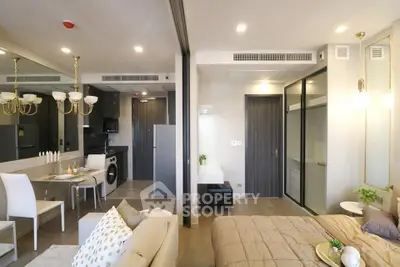Modern open-plan living room and bedroom with elegant decor and dining area in a stylish apartment.