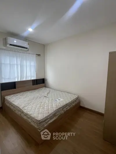 Cozy bedroom with wooden flooring and air conditioning, perfect for restful nights.