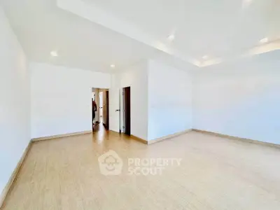 Spacious empty room with wooden flooring and white walls, ideal for customization.