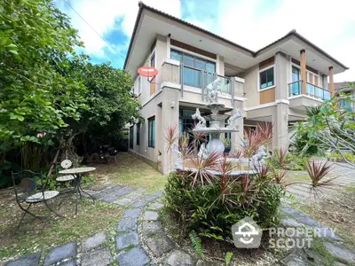 Charming two-story house with lush garden and elegant outdoor seating area.