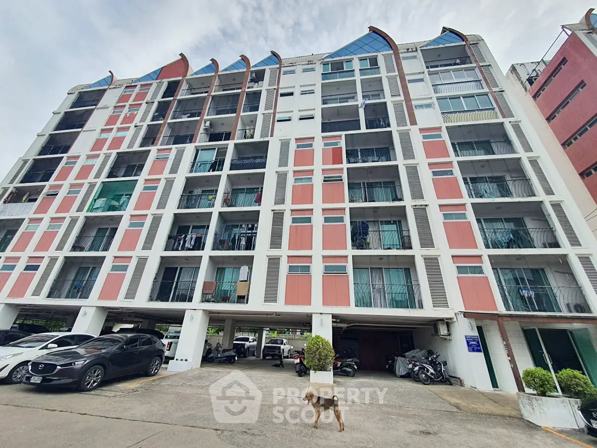 Modern multi-story apartment building with parking area and urban surroundings.