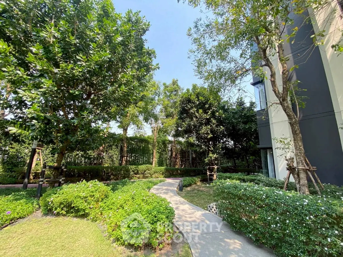 Lush garden pathway beside modern building exterior, perfect for relaxation and outdoor enjoyment.
