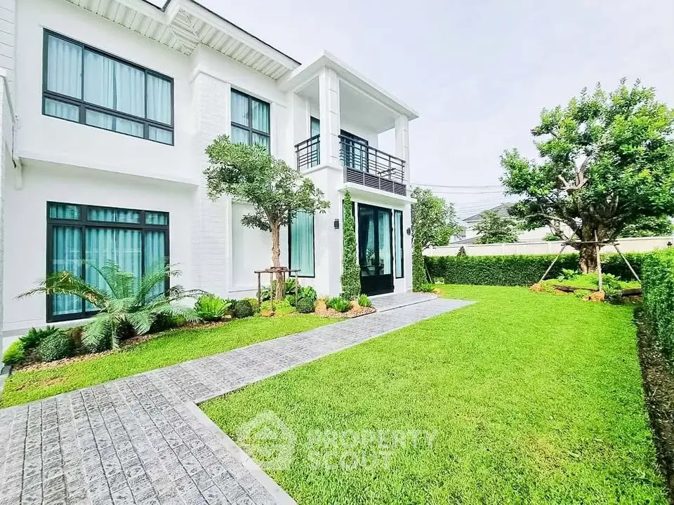 Elegant white two-story house with lush green lawn and modern landscaping