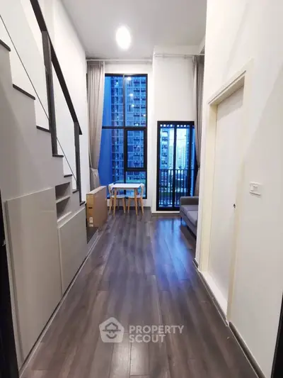 Modern duplex apartment with high ceilings and large windows offering city views.