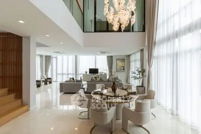 Luxurious open-plan living and dining area with high ceilings and elegant chandelier.
