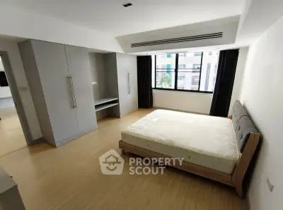 Spacious bedroom with large window and built-in wardrobe in modern apartment