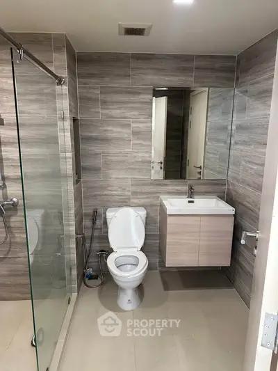 Modern bathroom with sleek design, featuring glass shower and stylish vanity.