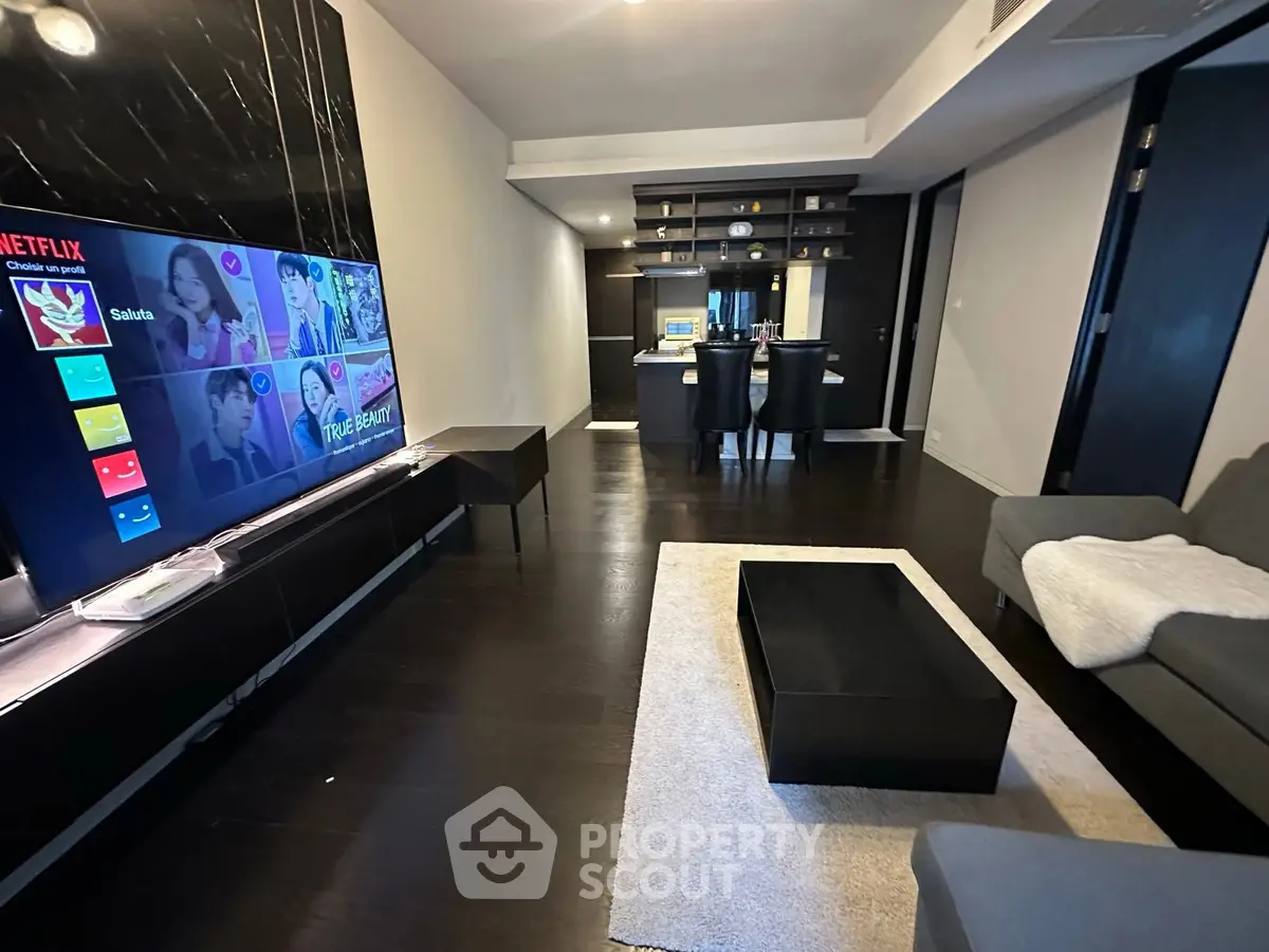 Modern living room with sleek dark flooring and open kitchen layout
