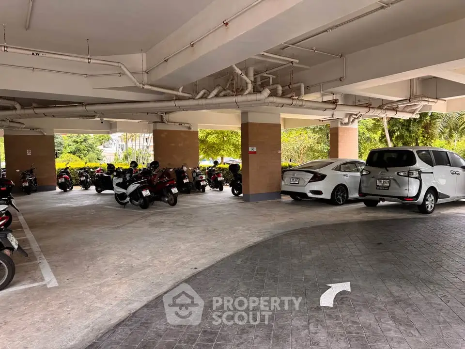 Spacious parking area with cars and motorcycles in a residential complex.