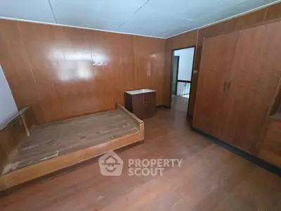 Spacious bedroom with wooden paneling and built-in wardrobe, ideal for cozy living.