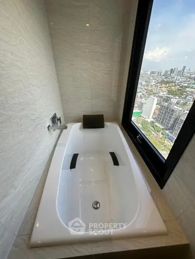 Luxurious bathroom with modern bathtub and stunning city view through large window.