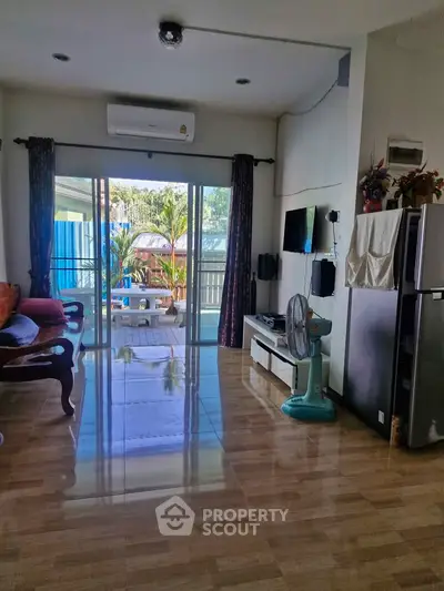 Spacious living room with modern decor and large sliding glass doors leading to a balcony with outdoor seating.