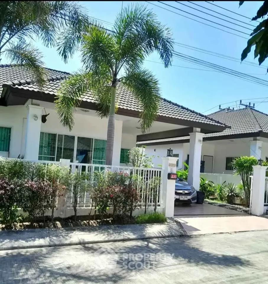 Charming single-story house with lush garden and driveway in tropical setting.