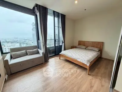 Spacious bedroom with city view and modern furnishings in high-rise apartment.
