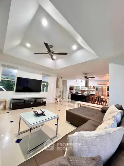 Spacious modern living room with open kitchen and stylish ceiling fan