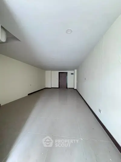 Spacious empty room with tiled flooring and neutral walls, ideal for customization.