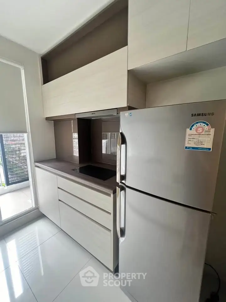 Modern kitchen with sleek cabinetry and stainless steel fridge in a bright apartment.
