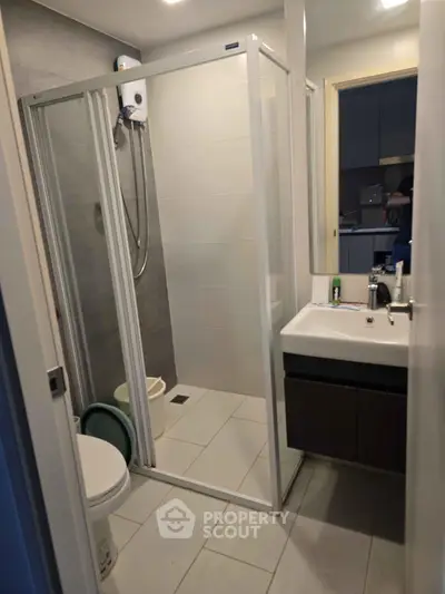Modern bathroom with glass shower enclosure and sleek vanity in compact layout.